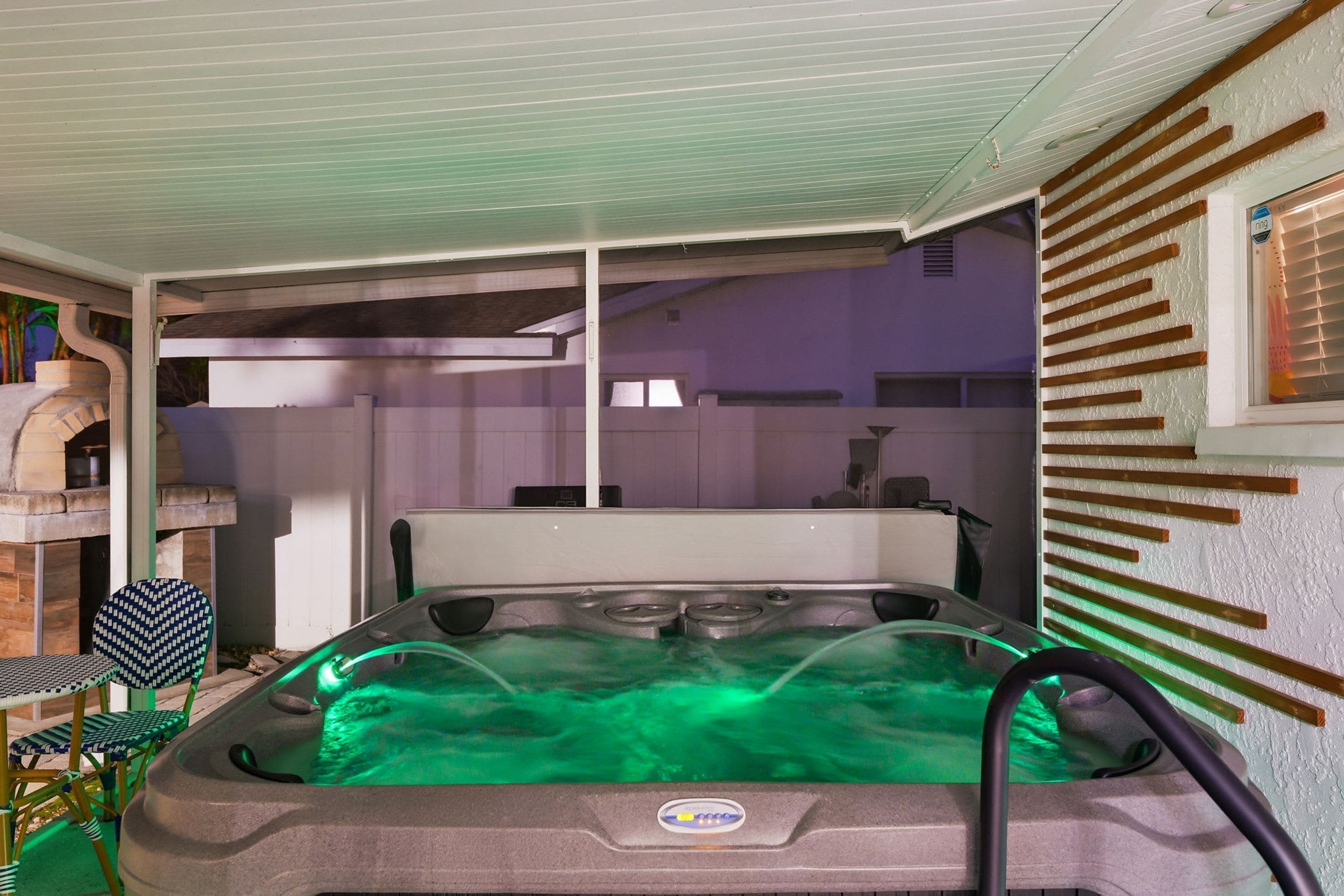 Un jacuzzi con panel de control, rodeado por un porche cubierto con sillas.