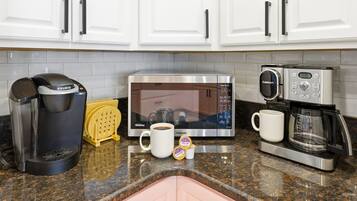 A kitchen with a coffee maker, microwave, toaster, and a coffee cup.