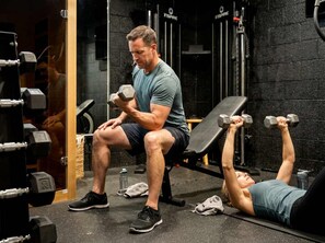 Ett gym med utrustning för styrketräning och träningsbänkar.