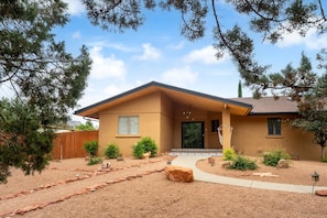 A single-story house with a sloped roof, a front porch, and a landscaped front yard with rocks and shrubs. - Sedona Haven 7BR Sleeps 24 Sauna Hot Tubs (Sedona)