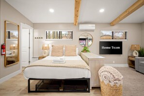 A bedroom with a bed, bedside lamps, a mirror, a wall-mounted air conditioner, and a framed 'Home Team' sign. - Sedona Haven 7BR Sleeps 24 Sauna Hot Tubs (Sedona)