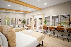 A hotel room with a bed, a seating area with a table and chairs, and large windows with blinds. - Sedona Haven 7BR Sleeps 24 Sauna Hot Tubs (Sedona)