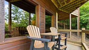 A wooden deck with two Adirondack chairs and a table, overlooking a forested area. - Mtn Cabin w Hot Tub Game Room Grill Views (Blue Ridge)