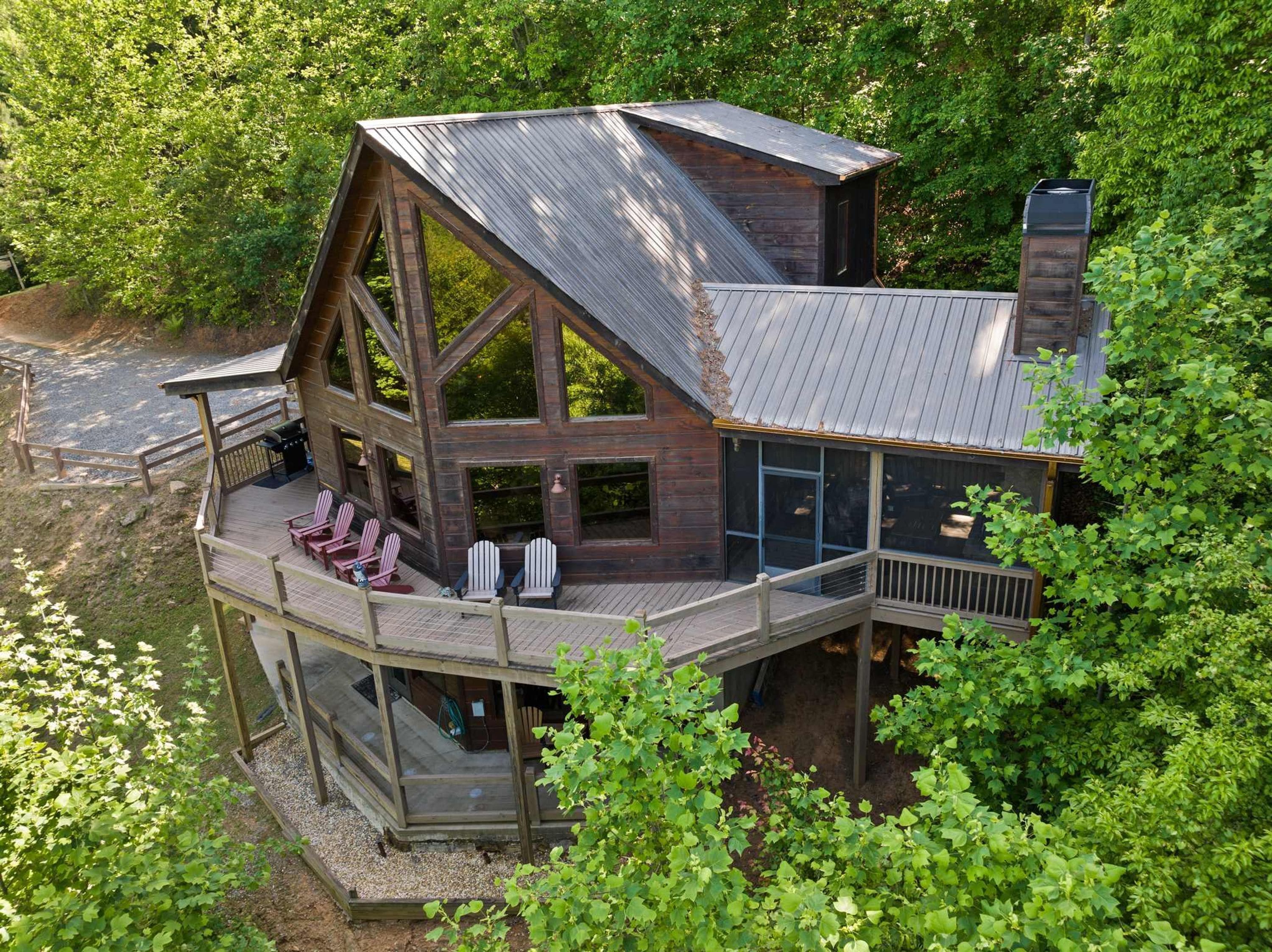 A cabin with a large deck, multiple windows, and a chimney.