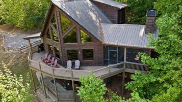 A cabin with a large deck, multiple windows, and a chimney.