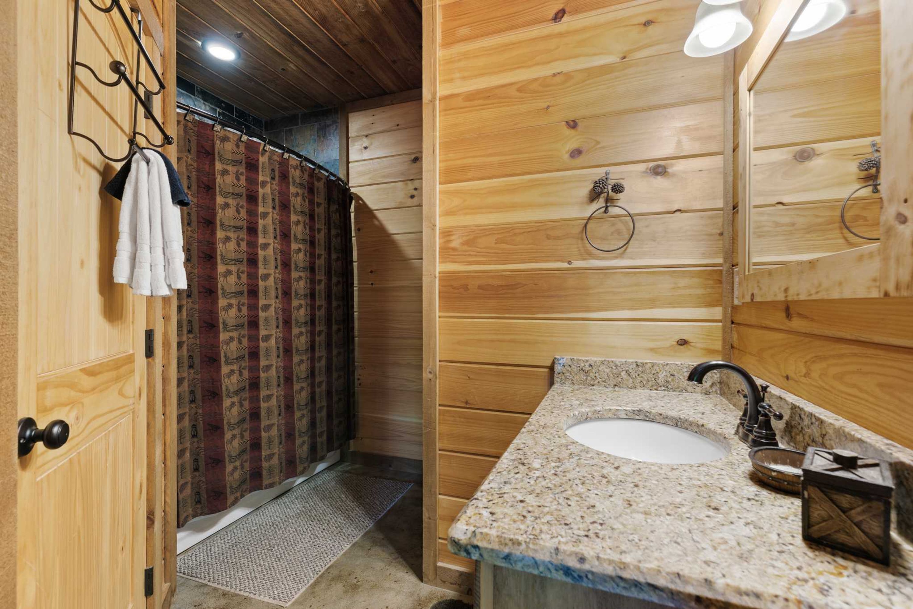 Un intérieur en bois avec une salle de bain comprenant un lavabo, un miroir et un porte-serviettes.