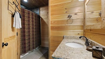 Un interior de madera con baño que incluye un lavamanos, espejo y toallero.
