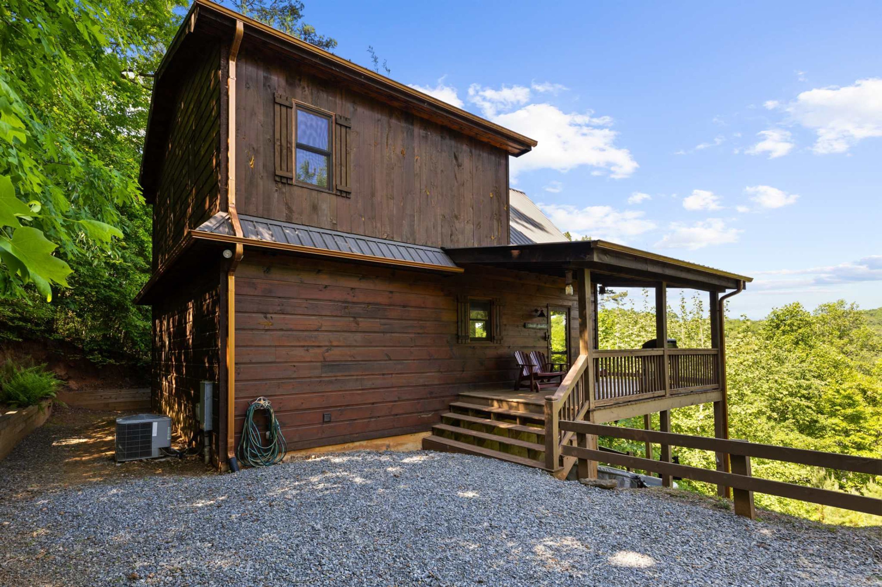 Une cabane en bois avec une véranda et une allée gravillonnée.