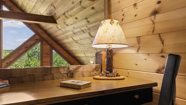 A wooden desk with a lamp, a book, and a window with a view of greenery. - Mtn Cabin w Hot Tub Game Room Grill Views (Blue Ridge)