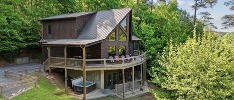 A two-story cabin with a balcony, surrounded by trees.