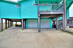 A two-story building with a covered parking area and a single garage door. - La Playa Paradise- Beach Access Large Island Home Pool Table (Port Aransas)