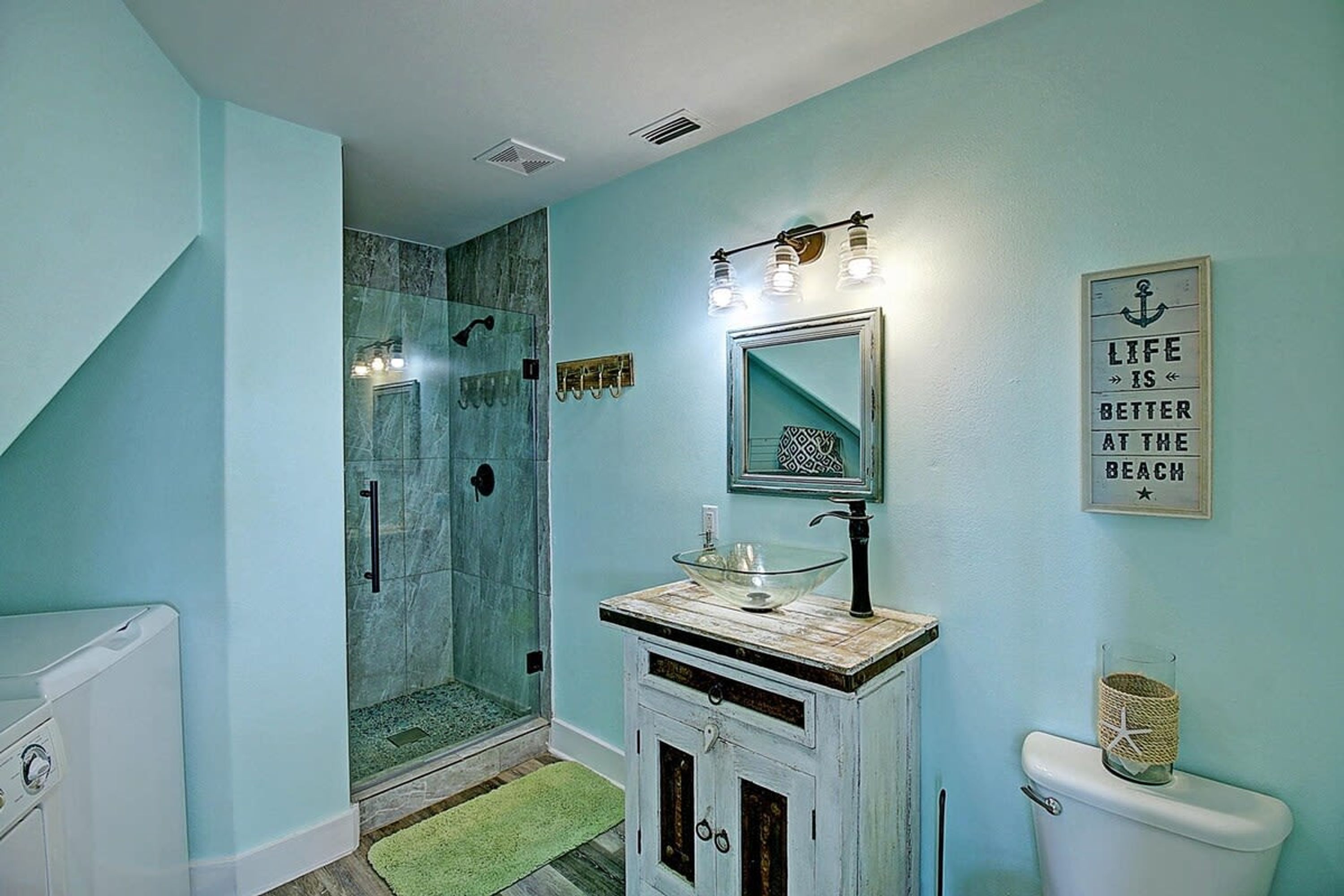 A bathroom with a glass shower, a sink with a mirror, and a toilet.