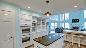 Un'ampia cucina con mobili bianchi, un'isola centrale e un'ampia finestra che offre luce naturale.