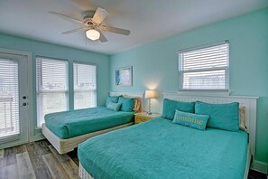 Ein Schlafzimmer mit zwei Betten, einem Deckenventilator und Fenstern mit Jalousien.