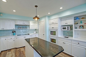 A kitchen with white cabinets, a granite island, and a hanging pendant light. - La Playa Paradise- Beach Access Large Island Home Pool Table (Port Aransas)