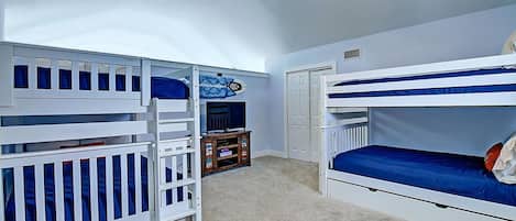 A room with bunk beds, a ceiling fan, and a small wooden cabinet.