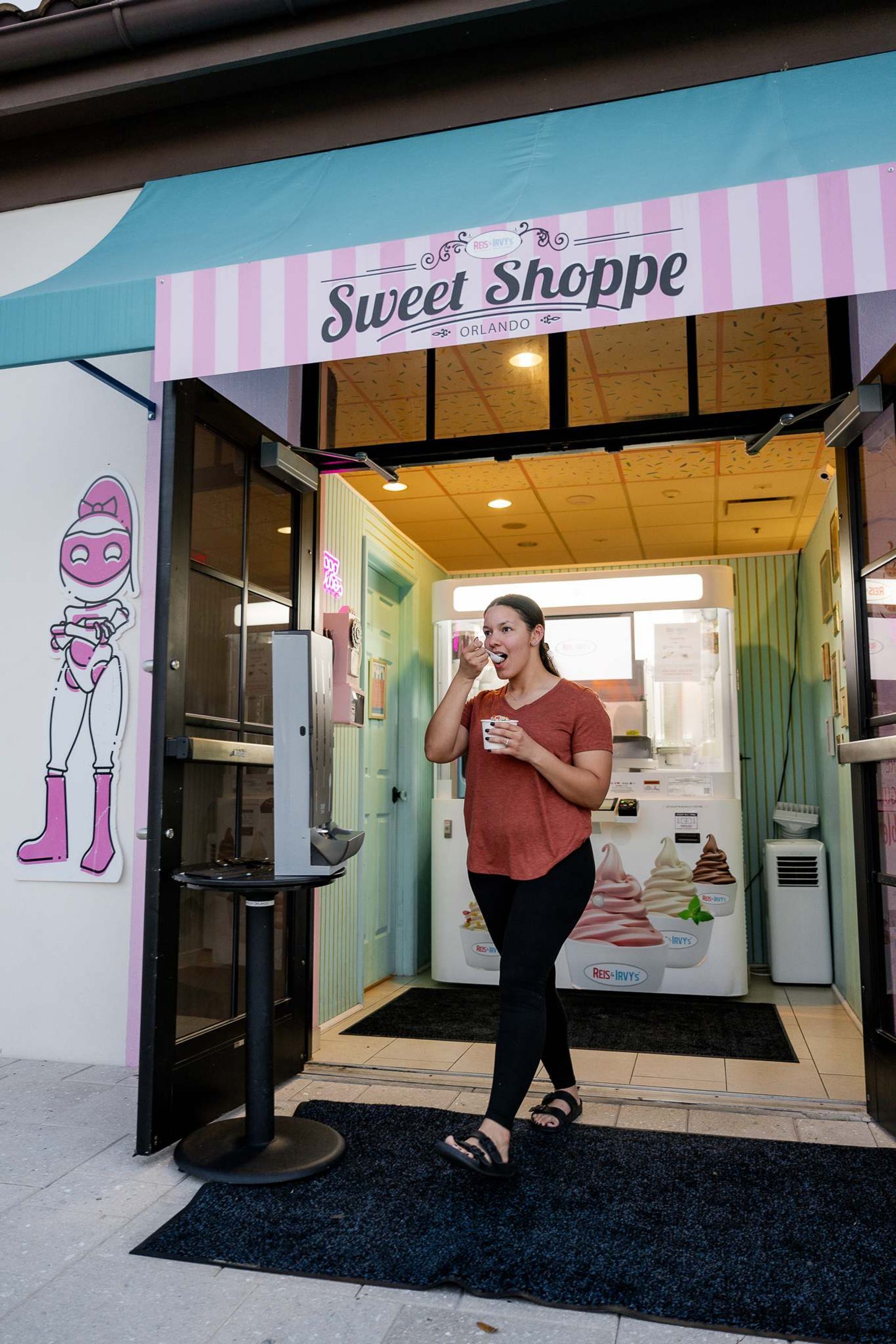 A storefront with a sign reading 'Sweet Shoppe' and a cartoon character on the wall.