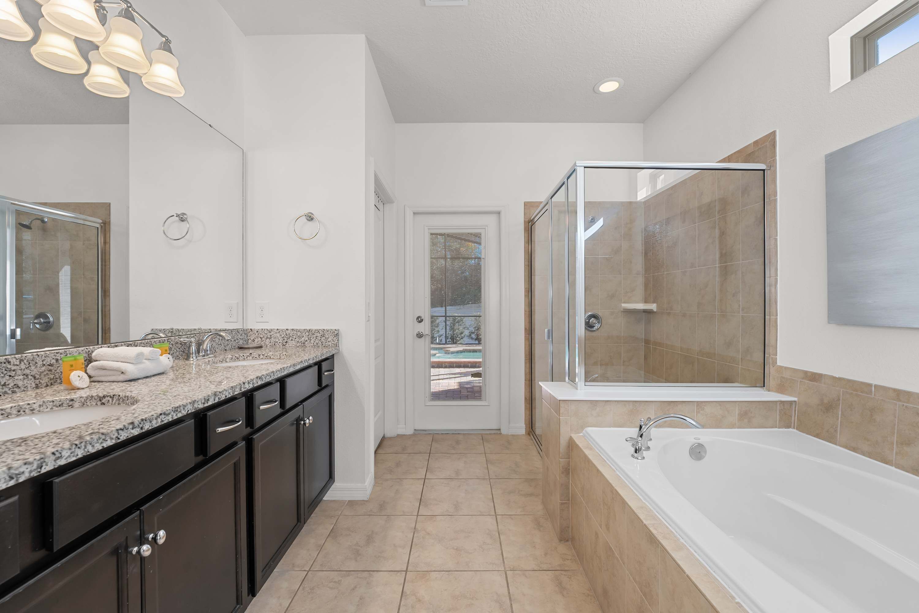 Un baño moderno con una ducha espaciosa, una bañera y un tocador con encimera de granito.