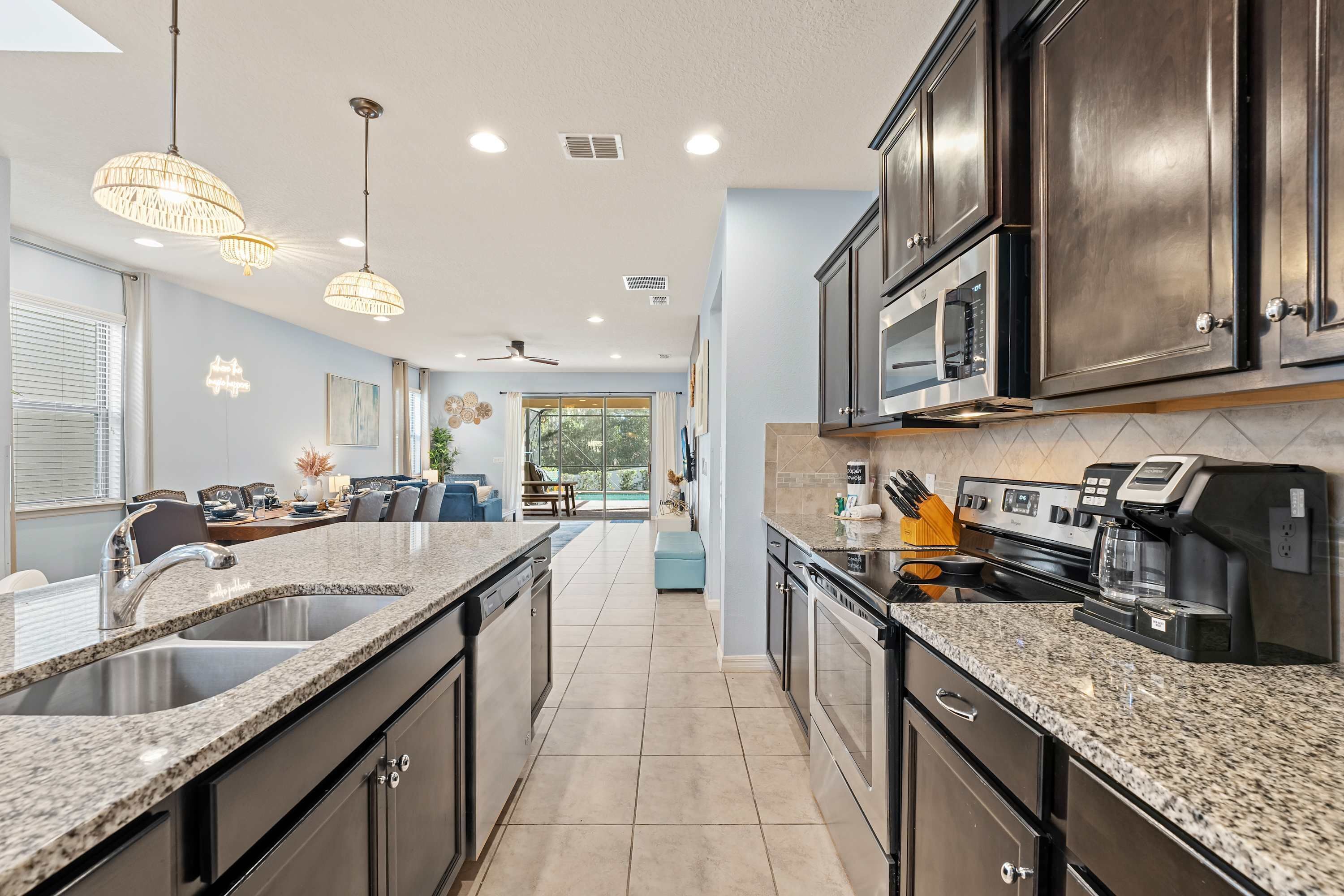 A modern kitchen with granite countertops, stainless steel appliances, and pendant lighting.