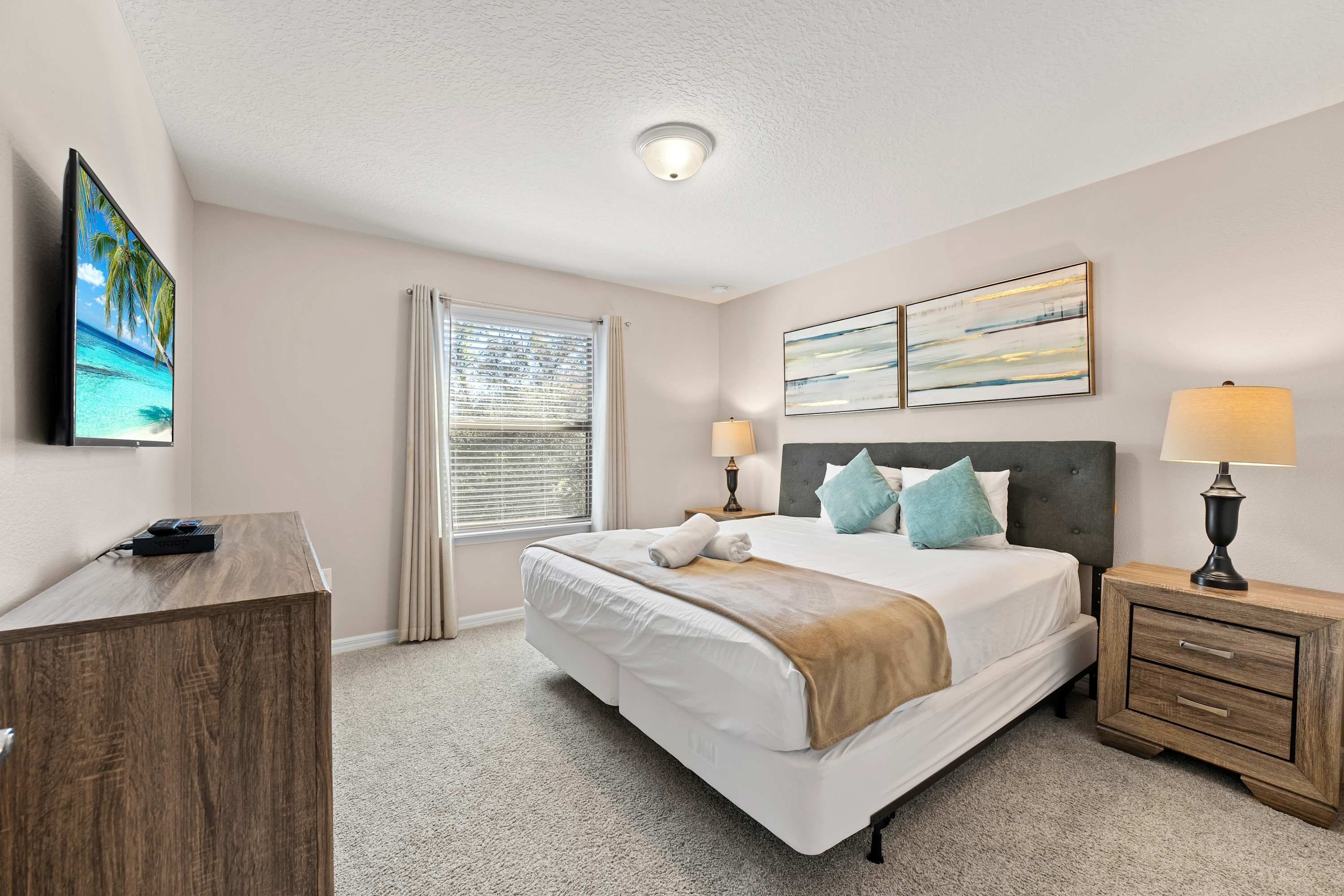 A hotel room with a bed, bedside tables, a desk, and a window with blinds.