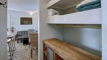 Un espacio habitable compacto con una litera, una pequeña zona de estar y un estante en la pared.