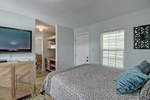 A bedroom with a bed, a television, a wardrobe, a door, and a window. - Kahuna Cottage- Family Friendly Fenced Yard (Port Aransas)