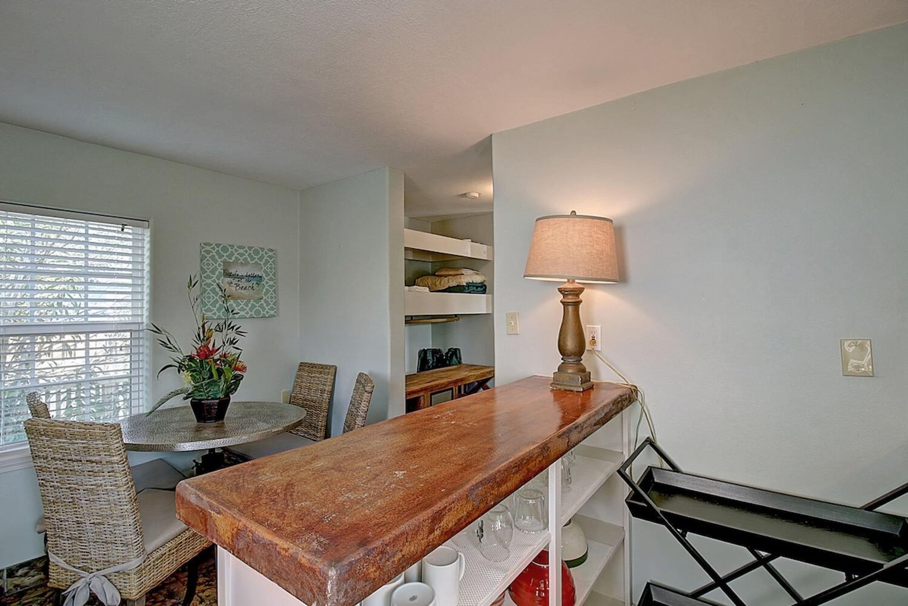 A dining area with a round table, chairs, a potted plant, and a lamp.