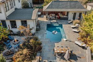 Ein wohnlicher Hinterhof mit Swimmingpool, Sitzgelegenheiten im Freien und einer Feuerstelle.