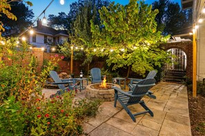 Eine Terrasse mit Sitzgelegenheiten im Freien, einem Feuerkorb und Lichterketten.