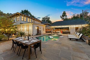 Ein Garten mit Pool, Essbereich und Gartenmöbeln.