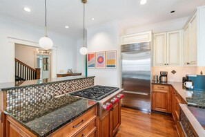 A modern kitchen with a central island, stainless steel appliances, wooden cabinets, and a tiled backsplash. - 6BR Home Private Pool Spa Games Gazebo (Memphis)