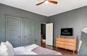 A bedroom with a bed, a dresser, a ceiling fan, and a TV on the wall. - 6BR Home Private Pool Spa Games Gazebo (Memphis)