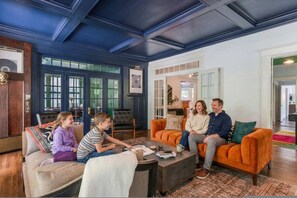 A family seated on a sofa in a room with a dark blue ceiling and wooden floors. - 6BR Home Private Pool Spa Games Gazebo (Memphis)