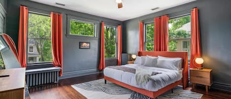 A bedroom with a large bed, a ceiling fan, and windows with curtains.