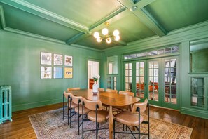 A dining area with a wooden table and chairs, a patterned rug, and green walls. - 6BR Home Private Pool Spa Games Gazebo (Memphis)