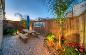A backyard with a wooden fence, a picnic table, and a sign that reads 'Sparkle Fish.' - Sparkle Fish Private Breezeway Resort Pool (Port Aransas)
