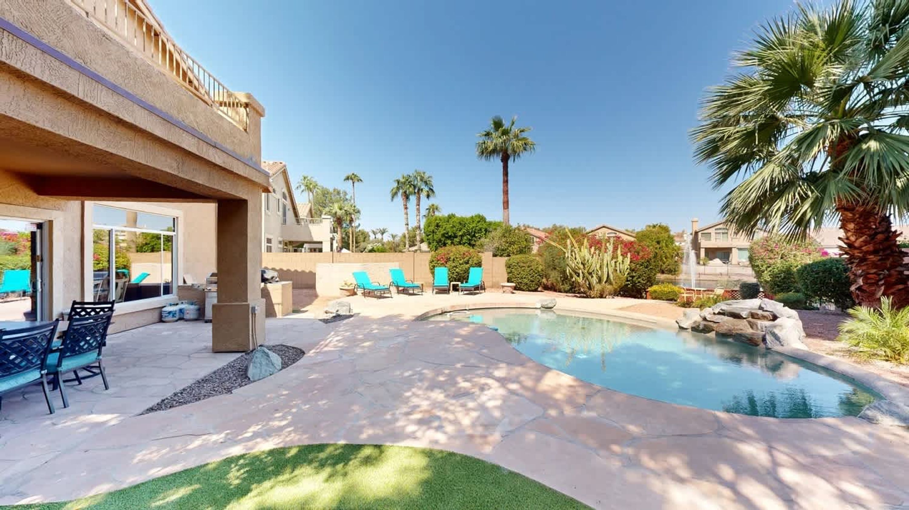 A swimming pool with lounge chairs, a patio area, and a view of a residential building.