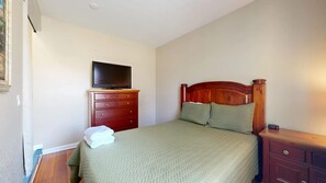 A bedroom with a bed, a dresser, a television on top of the dresser, and a bedside table with a clock. - Sleeps 10 Heated Pool Putt Putt Dogs Welcome (Chandler)