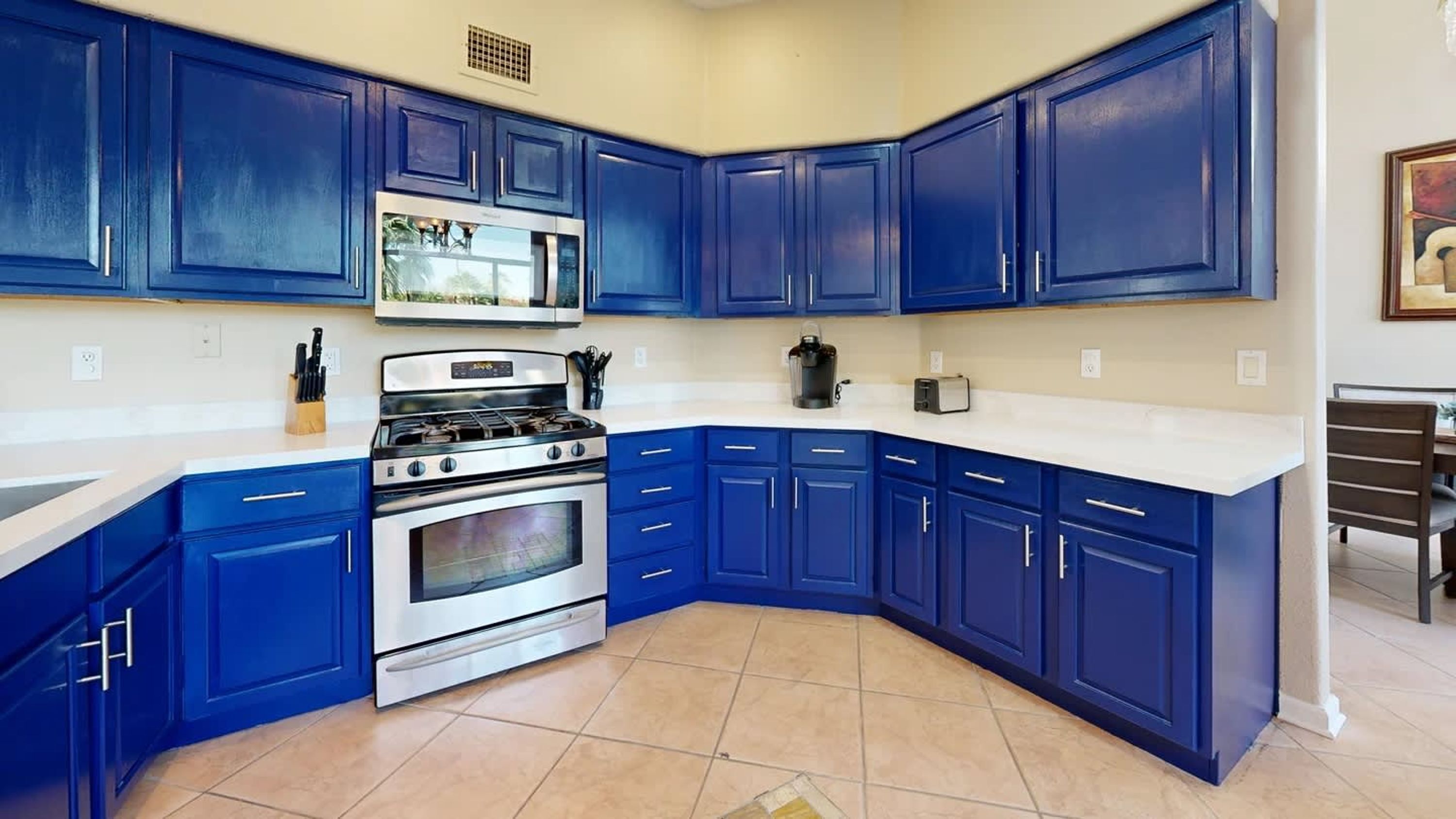 A kitchen with blue cabinets, a stainless steel stove, and a microwave.
