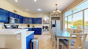 Cozinha moderna com armários azuis, uma ilha central e um espaço de jantar com vista.