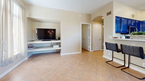 A spacious living area with a flat-screen TV, a kitchen with blue cabinets, and a dining area with two chairs. - Sleeps 10 Heated Pool Putt Putt Dogs Welcome (Chandler)