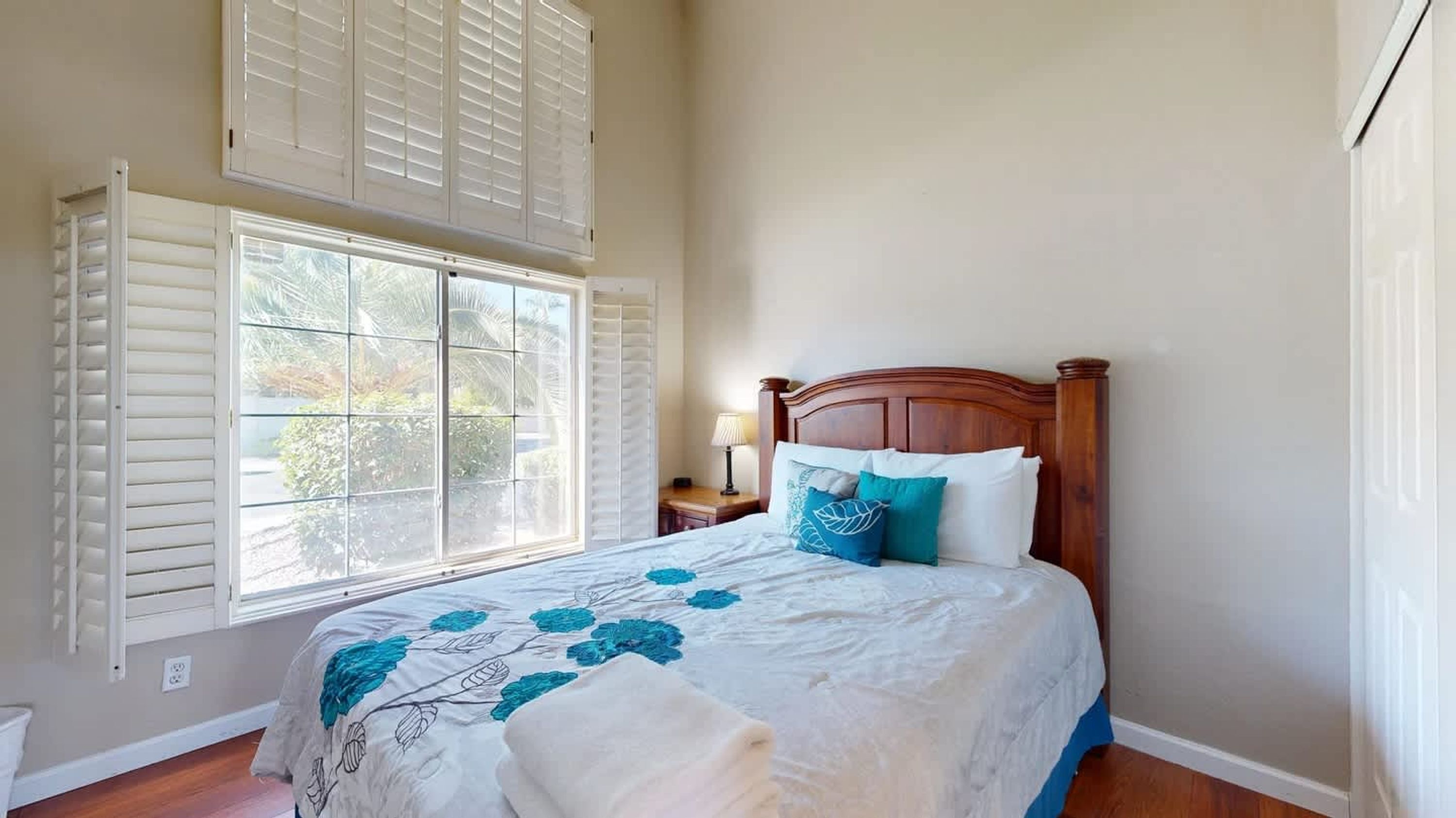 A bedroom with a bed, a nightstand, a lamp, and a window with blinds.