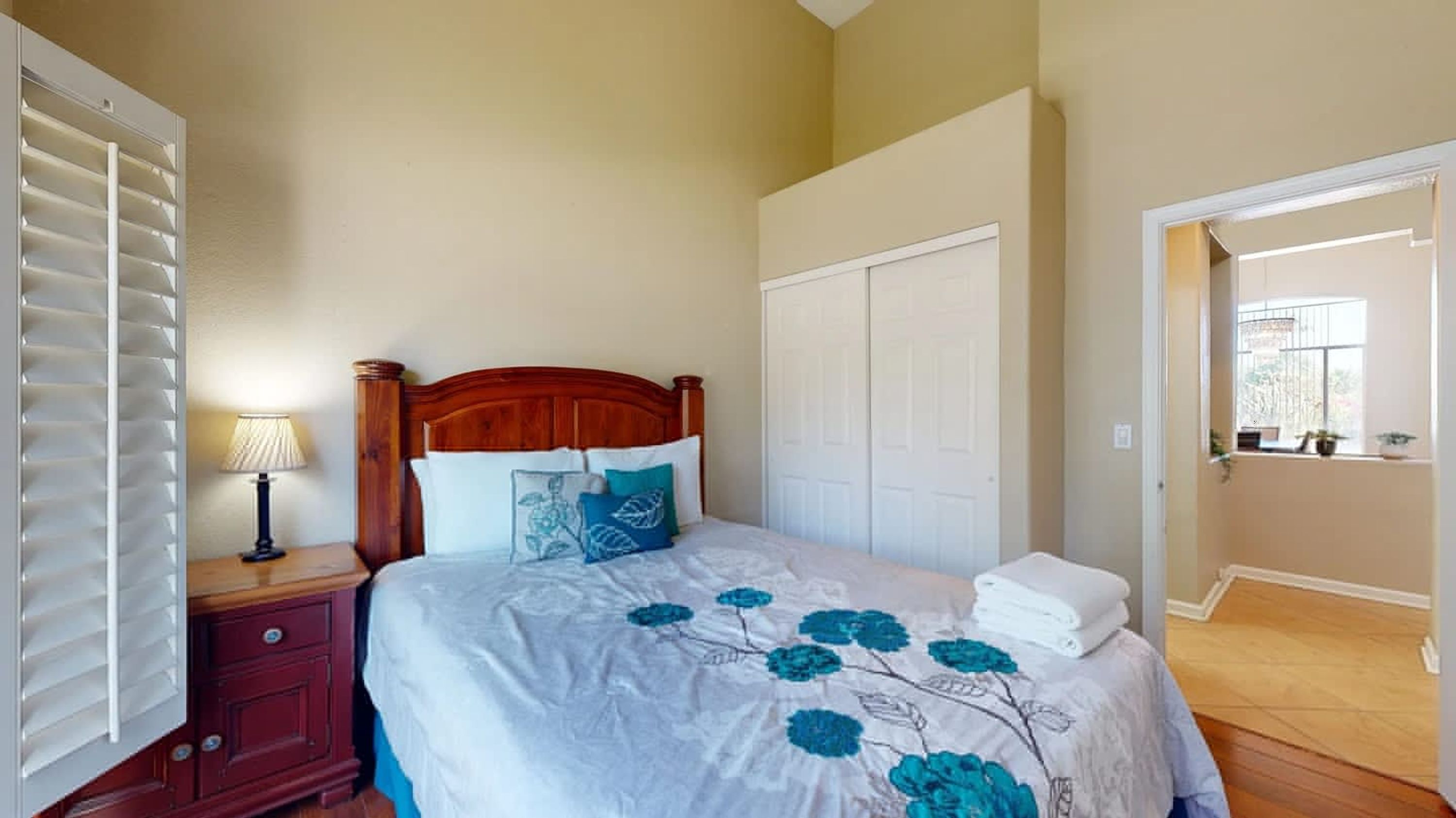 A bedroom with a bed, a nightstand, a dresser, and a closet.