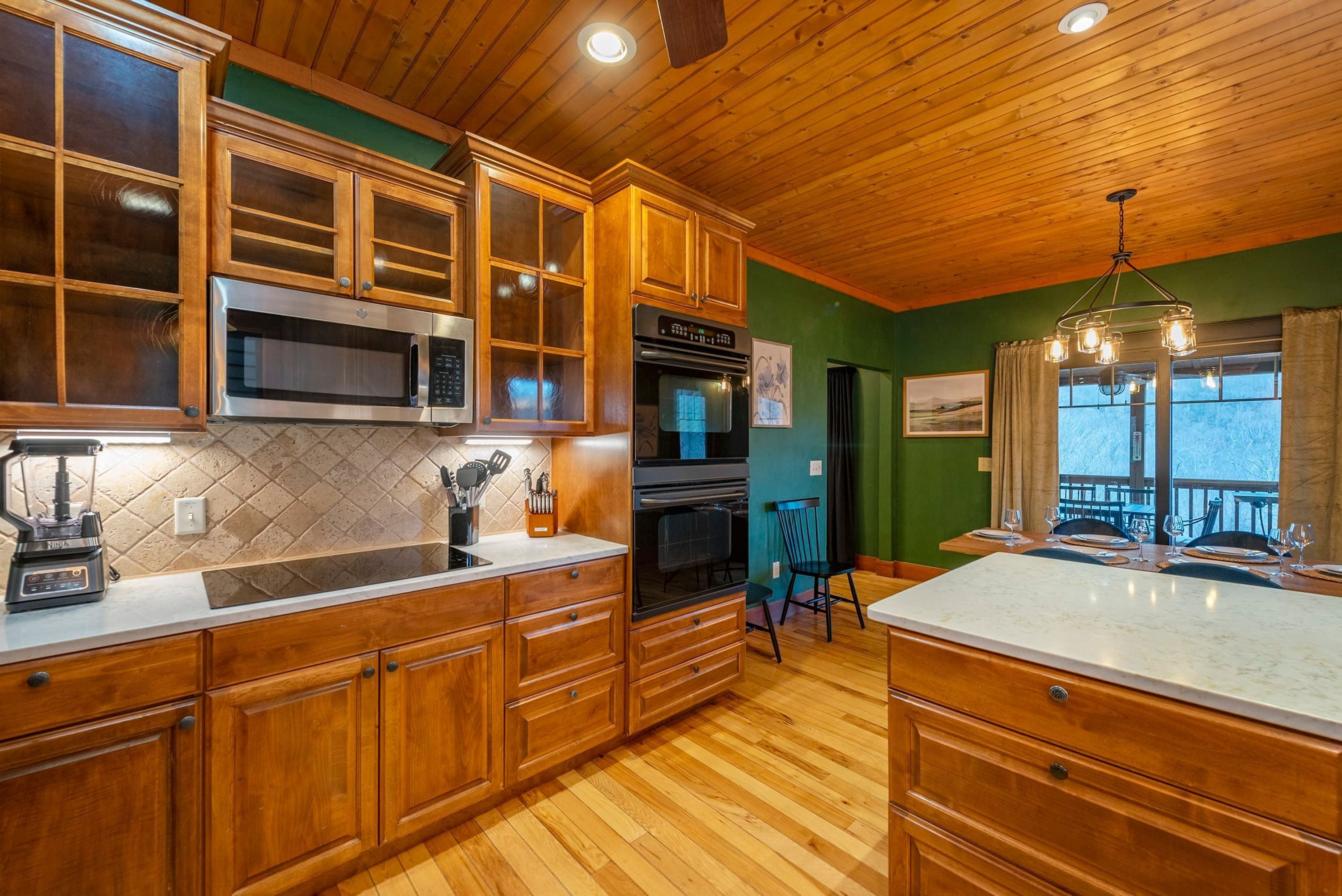 A kitchen with wooden cabinets, a microwave, an oven, and a dining area with a table and chairs.