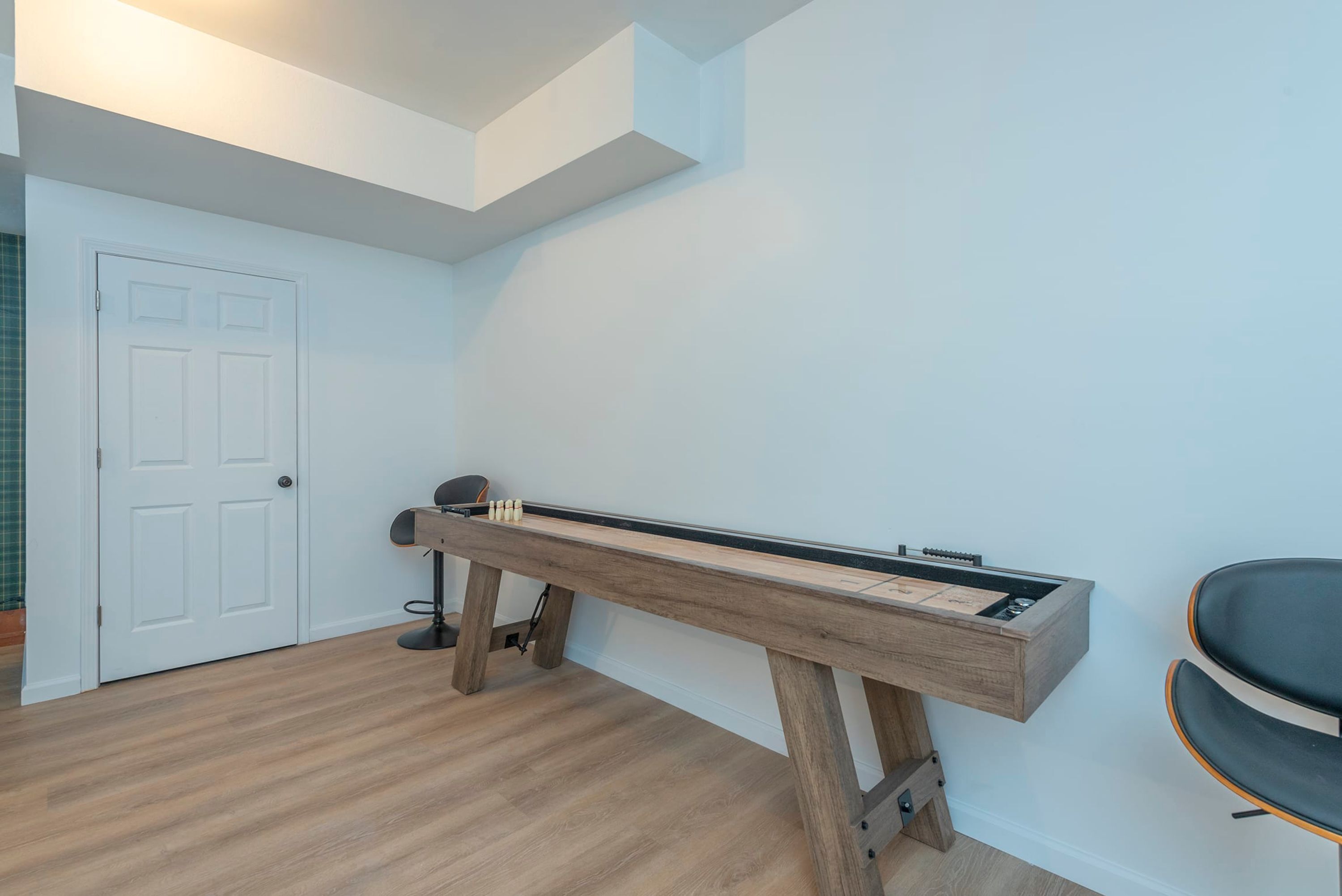 Una habitación con un piano, una puerta y un sillón fijado a la pared.