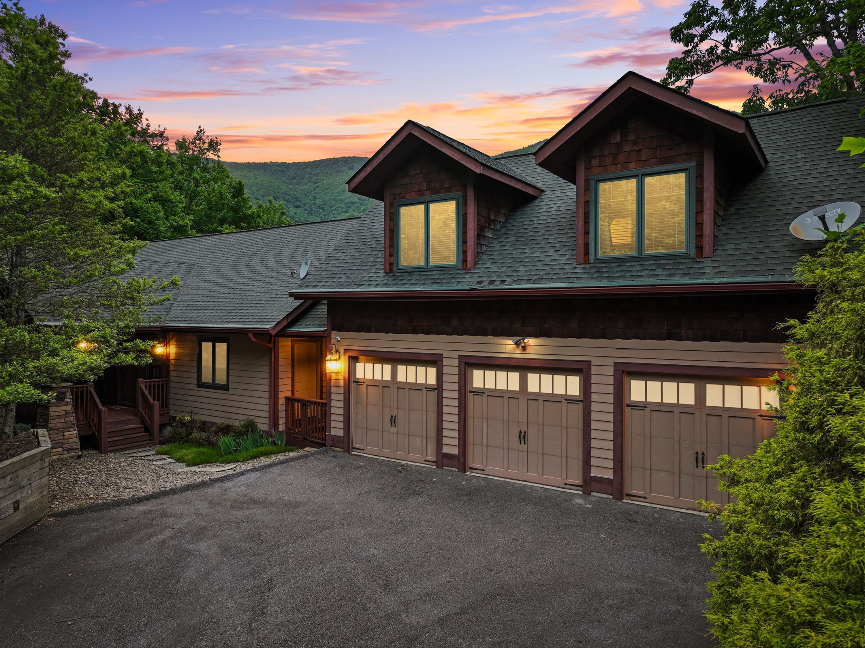 A two-story house with a garage, surrounded by trees and a clear sky.