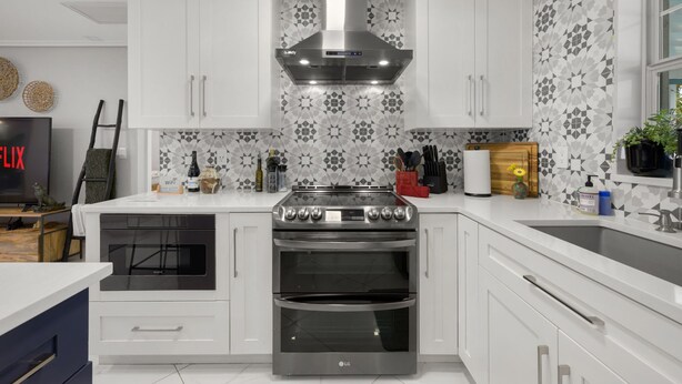 A modern kitchen with white cabinetry, a stainless steel range, and a patterned backsplash. - Coastin Close Family Fun HTD Pool Outdoor Games (Pinellas Park)