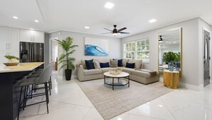 A modern living room with a sofa, coffee table, and a large window. - Coastin Close Family Fun HTD Pool Outdoor Games (Pinellas Park)