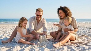 A family on a sandy beach with a clear sky and calm sea in the background. - Steps to the Beach Pool Courts Family Fun (Destin)