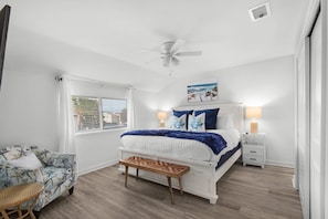 A bedroom with a bed, bedside tables, a ceiling fan, a window with blinds, and a wall-mounted picture. - Steps to the Beach Pool Courts Family Fun (Destin)